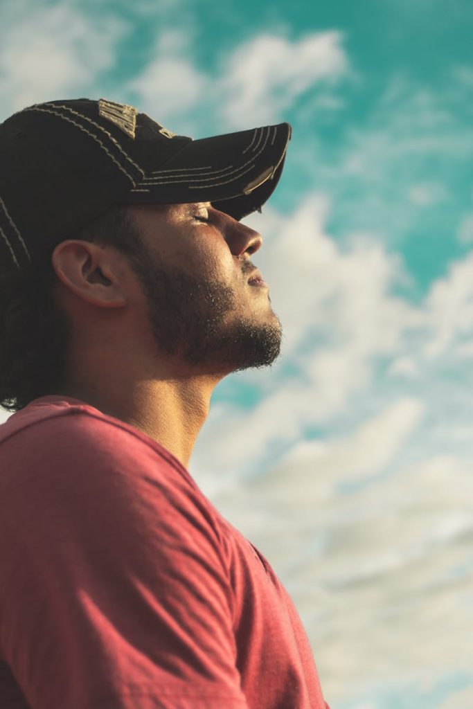 A man enjoys outdoor relaxation and mindfulness beneath a bright, cloudy sky, exuding calm and peace.